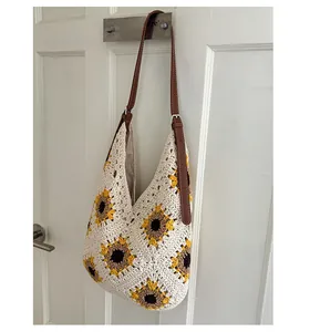 Detail of sunflower crochet knit pattern on an off-white hobo bag with leather strap
