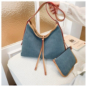 Detail view of denim tote bag set with brown leather trim and matching small pouch