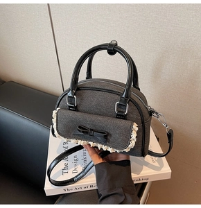 Close-up of grey denim balletcore bag with black leather bows and delicate lace trim