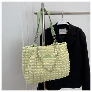 Detail of mint green ruched tote bag with pearl chain and floral metal charms