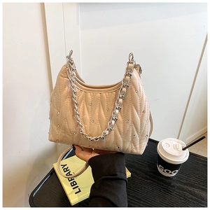Detailansicht der cremefarbenen Stepptasche mit glitzernden Strasssteinen und Kette