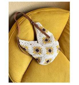 Detail of hand-knitted sunflower pattern on off-white crochet bag with leather strap