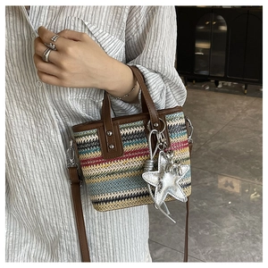Detail of colorful bohemian woven rainbow straw bag with leather trim and star charm