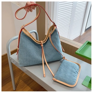 Detailed shot of denim hobo tote set with khaki leather straps on a metal bench