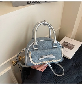Detailed shot of denim shell bag with white lace trim and silver bow accent