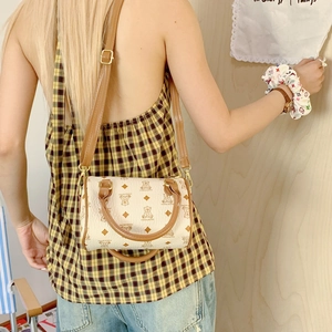 Side view of cream Boston bag with bear patterns and brown leather straps on model