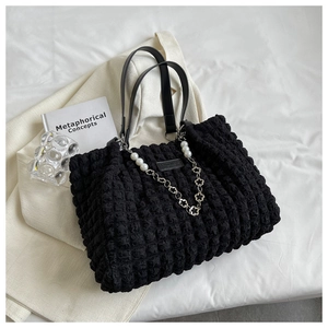 Detail of black popcorn texture tote bag with pearl chain and sleek shoulder strap