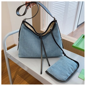 Close-up of washed denim hobo bag with brown leather trim and matching small pouch