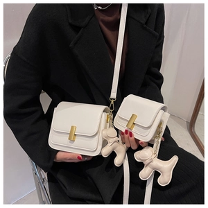 Detail of white ivory crossbody bags in two sizes with gold buckle and puppy charm