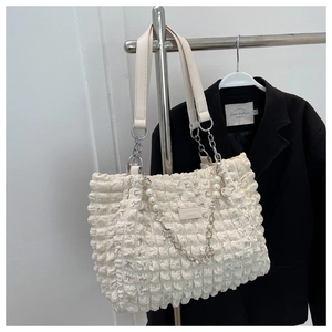 Detail of creamy white bubble textured tote bag with pearl and silver chain decorations