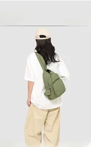Sage green canvas crossbody chest bag showing functional zippers and adjustable strap