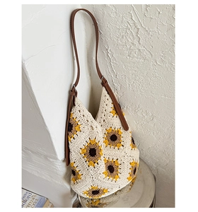 Detailed view of hand-knitted sunflower pattern on beige shoulder bag with leather strap