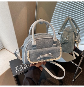 Detail of blue denim shell bag with lace trim, bow pocket and silver metal zipper