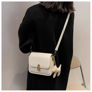 Detail of white mini square bag with gold twist lock and matching puppy charm