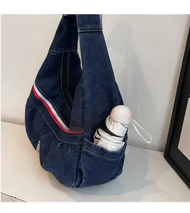Detail of navy denim tote bag showing side pocket with a white folding umbrella inside