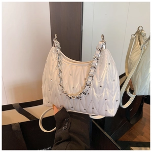 Details einer weißen Stepptasche mit Kristallverzierung und silbernem Kettenhenkel