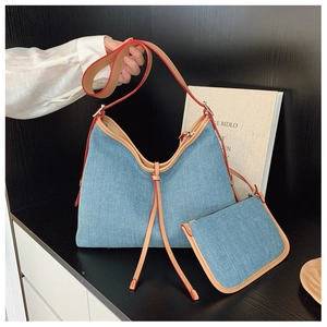 Detail of blue denim hobo tote bag featuring brown leather straps and red edge paint