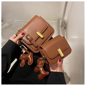 Detail of vintage brown crossbody bags with gold metal clasps and dog bag charms