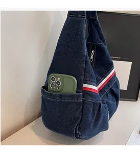 Detail of blue denim tote bag with side pocket holding a smartphone and striped strap