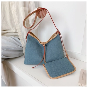 Detail of denim tote bag and small matching pouch with red leather straps in a home setting