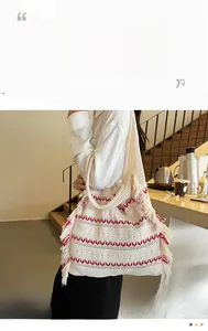 Detailed view of cream-colored knit tote bag with red wave patterns and fringe edge