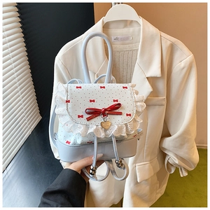 Close-up of light blue polka dot lace backpack with red bow and gold heart pendant
