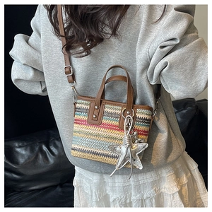 Close-up of colorful striped straw bucket bag with brown leather strap and star charm