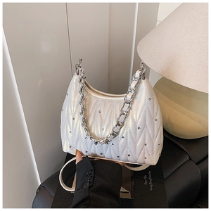 Detailaufnahme einer schillernd gesteppten Handtasche mit Wellentextur und Strasssteinen