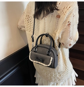 Detail of grey tweed shell bag with lace trim and black bow on a wooden staircase