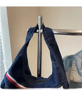 Detail of navy blue denim shoulder bag with red, white, and blue striped webbing straps