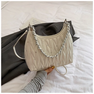 Detail der cremefarbenen Stepptasche mit silberner Kette und funkelnden Strasssteinen