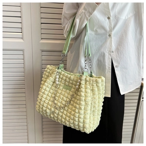 Detail of popcorn textured tote bag with green leather strap and pearl chain decoration