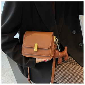 Detailed side view of a brown vintage leather crossbody bag with a cute dog-shaped charm