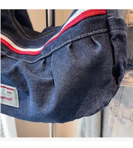 Detail of navy denim tote bag featuring red and white striped trim and woven brand patch
