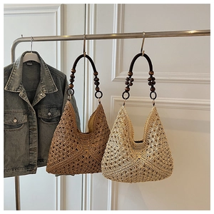 Detail of hand-woven straw tote bag with round wooden handle and beaded accents