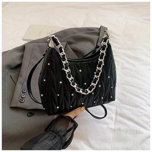Detailansicht einer schwarzen Stepptasche mit silbernen Nieten und einer Metallkette