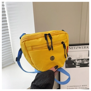 Dettaglio della borsa a tracolla in tela gialla con cinturino blu e tasche a zip