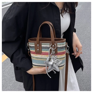 Detail of multi-color woven straw bucket bag with leather handles and silver star charm