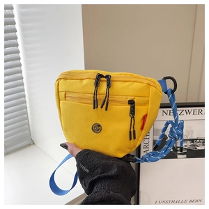 Dettaglio della borsa a secchiello gialla in tela con tracolla blu e multi-tasche