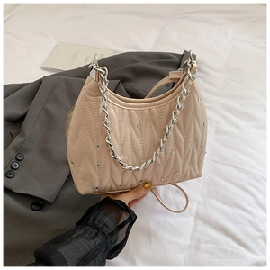 Detail der beigen gesteppten Kunstledertasche mit Silberkette und Strasssteinverzierung