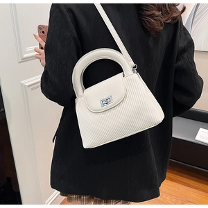 Detail of white pleated leather bag with silver metal clasp and curved top handle