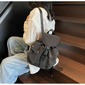 Detailansicht des schwarz-weiß karierten Rucksacks mit Klappverschluss und Seitentasche