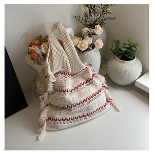 Close-up of bohemian knit tote bag with red geometric patterns and fringe detail