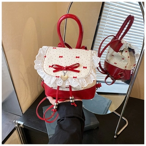 Detail of red and cream Lolita backpack featuring lace trim and heart pendant charm