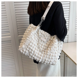 Detail of white popcorn texture tote bag with pearl chain and fashion bag label