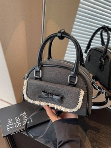Chic shell-shaped grey crossbody bag with lace trim and bow accent in a mirror display