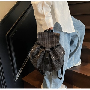 Detailansicht eines karierten Rucksacks mit Schnallenverschluss auf einer Holztreppe