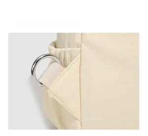 Detail of durable silver D-ring buckle on light beige nylon backpack fabric