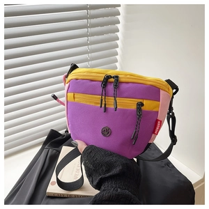 Dettaglio di una borsa a tracolla in nylon impermeabile viola e giallo con cinturino