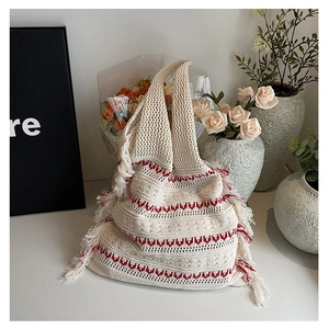 Detail of bohemian knit tote bag with red geometric patterns and long tassel fringe edge